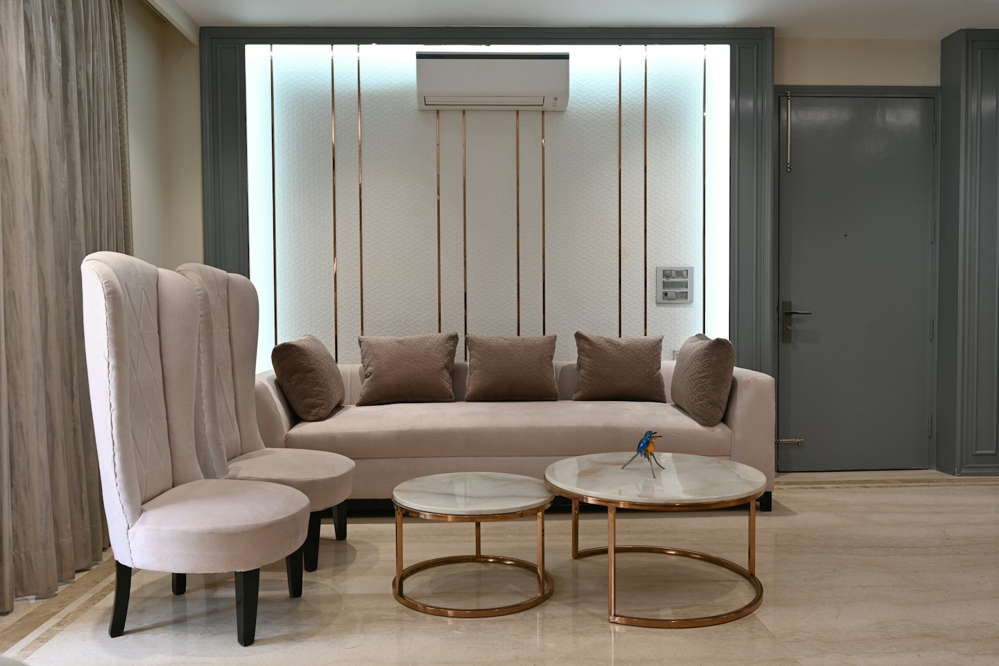 Sala de estar moderna con sofá beige y mesas de centro de mármol.