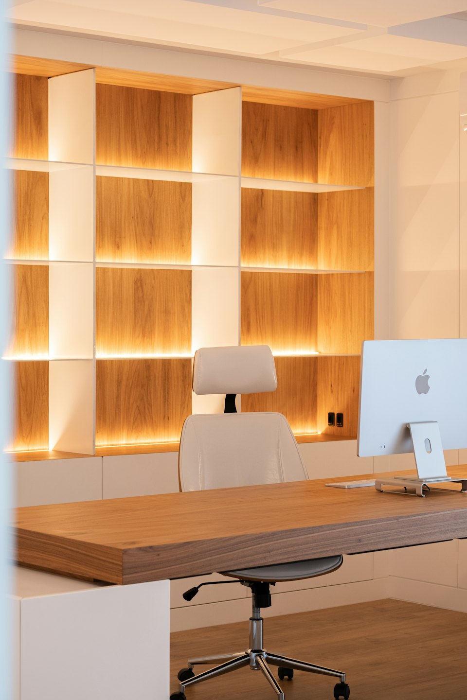 Silla de oficina ergonómica vacía junto a un escritorio de madera.