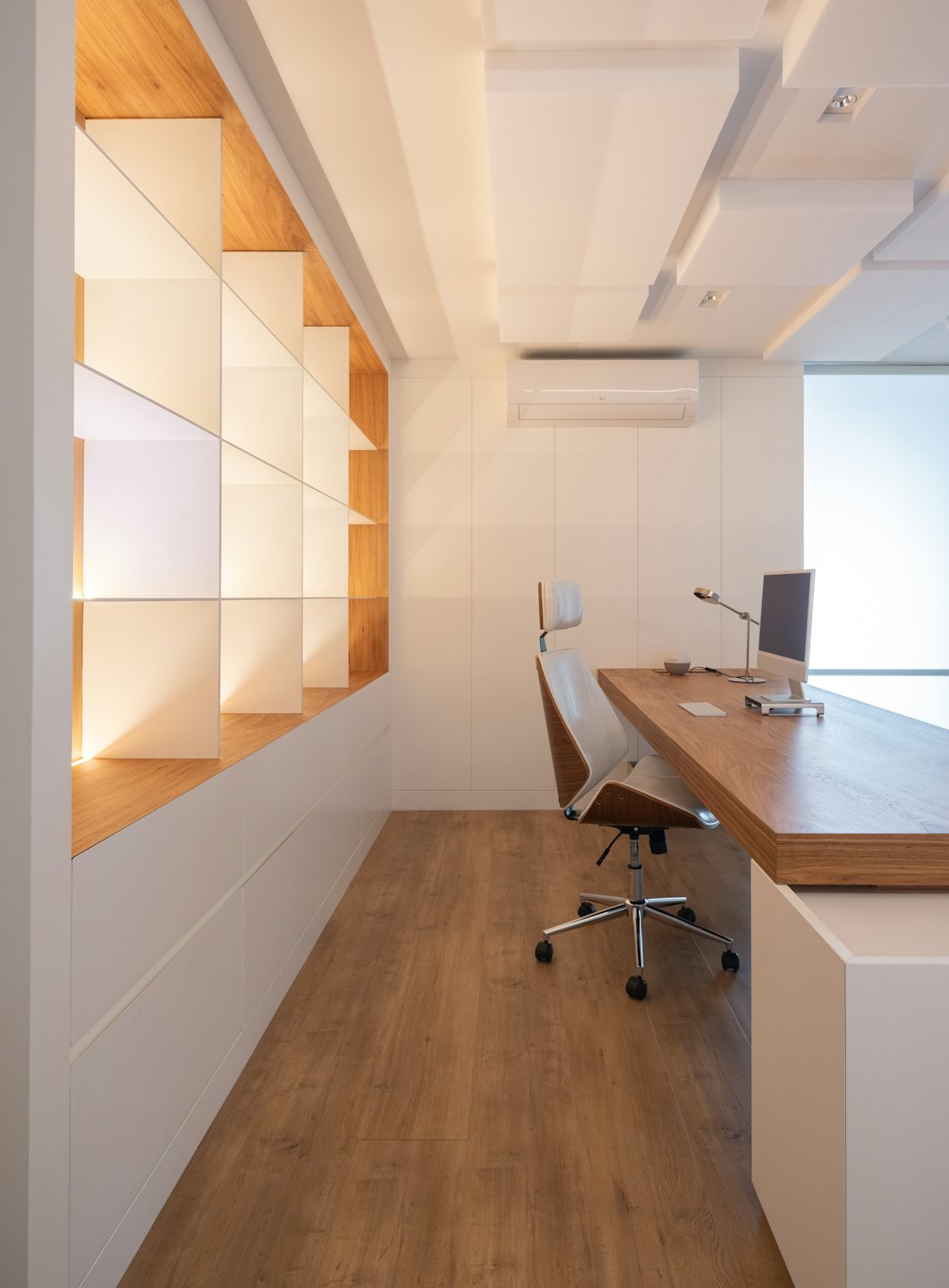 Oficina moderna en casa con escritorio de madera y computadora.