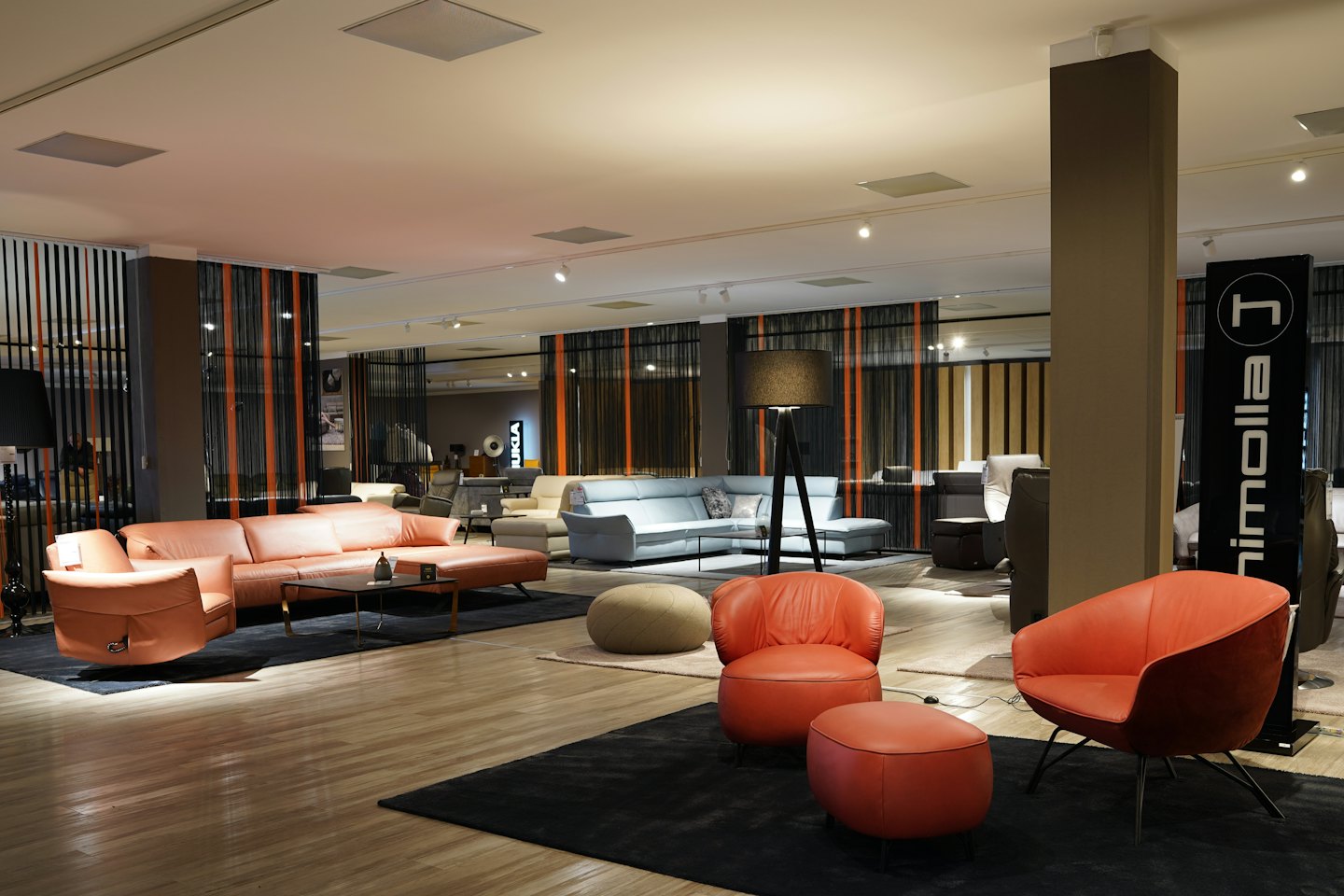 Sala de exposición de muebles modernos con sofás y sillones de cuero sobre alfombras.