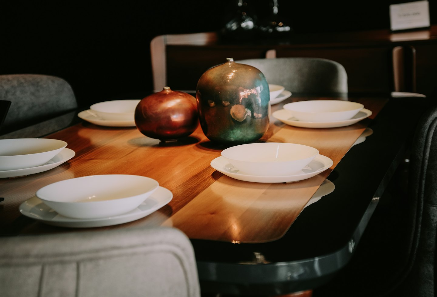 Conjunto de mesa de comedor moderna con vajilla blanca y jarrones metálicos.